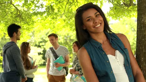 Estudiante-feliz-posando-y-amigos-hablando-detrás-de-ella