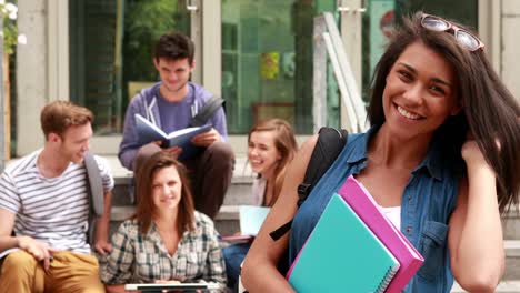 Pretty-student-posing-and-friends-studying-behind-her