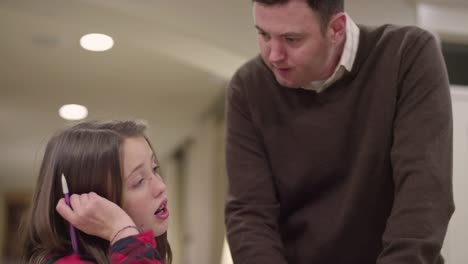 A-father-helping-his-daughter-with-her-homework-in-the-kitchen