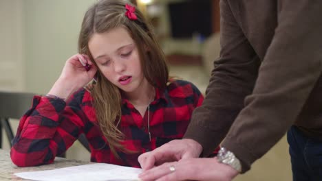 A-father-helping-his-daughter-with-her-homework-in-the-kitchen