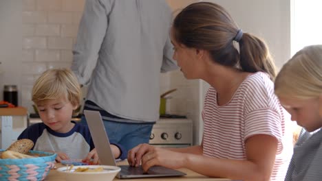 Kinder-arbeiten-am-Küchentisch-mit-Mama,-während-Papa-kocht