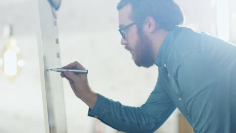 Creative-Young-Man-wearing-Glasses-Draws-Charts-on-His-Whiteboard.