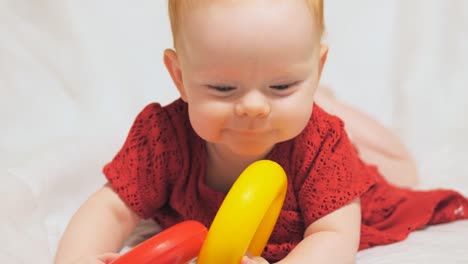 Kleines-Baby-in-einem-roten-Kleid-mit-Spielzeug-spielen