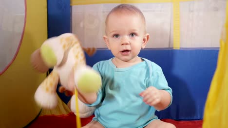 Boy-hugging-stuffed-deer-and-lion.-Attractive-baby-playing-in-the-children's-colorful-tent-in-the-house