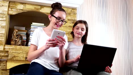 friends-socializing-at-home-and-playing-games-on-laptop-and-tablet,-girls-sitting-together