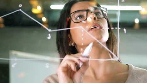 Young-attractive-female-office-worker-writing-on-glass-whiteboard