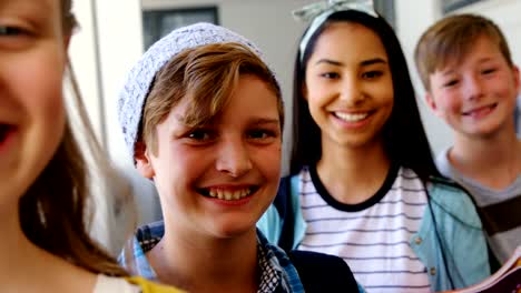 Smiling-students-standing-with-notebook-in-corridor