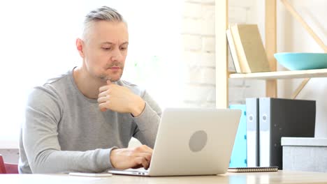 Middle-Aged-Man-Thinking-and-working-on-Laptop