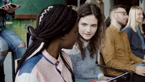 Equipo-de-negocios-creativos-jóvenes-en-conferencia-en-la-oficina-moderna.-Dos-colegas,-africano-y-caucásica-mujer-hablando