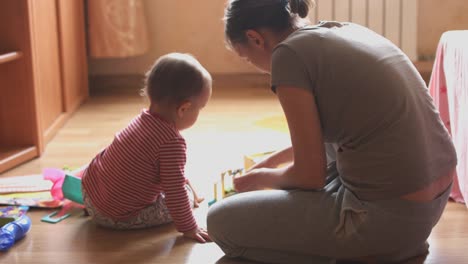 Madre-y-niño-jugando-en-la-sala-sentados-en-el-suelo.