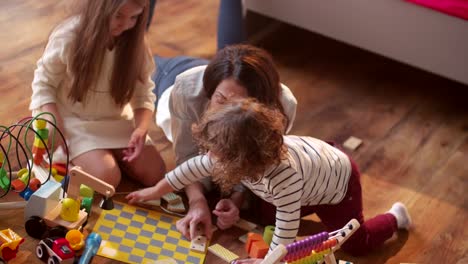 Kleine-Kinder-spielen-messily-mit-ihrer-Mutter-auf-dem-Boden