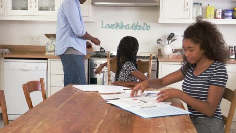 Padre-de-dos-hijas-ayudar-a-sentarse-en-la-mesa-haciendo-la-tarea