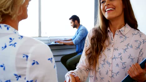 Female-executives-shaking-hands-while-interacting-with-each-other