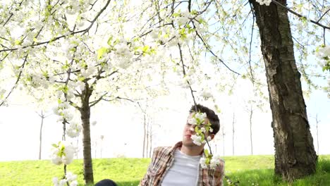 Joven-estudiante-estudiar-el-tema-con-un-ordenador-portátil-en-el-jardín-de-primavera