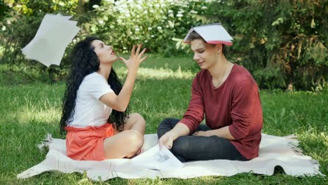 Tired-students-try-to-learn-educational-material-in-park-on-green-grass