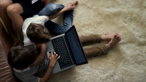 Zwei-jungen-spielt-am-Laptop-sitzen-auf-Teppich-zu-Hause