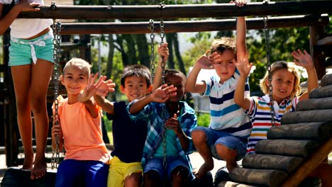 Portrait-of-happy-schoolkids-waving-hands-in-playground