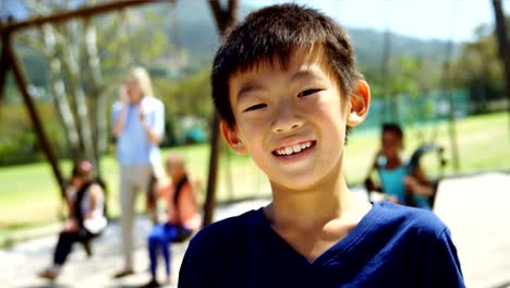 Portrait-of-happy-schoolboy-standing-in-playground