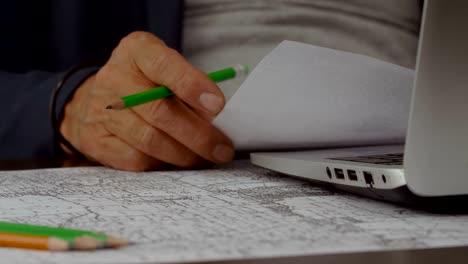 Hands-of-business-man-working-with-laptop,-cards-and-maps