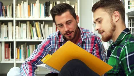 Zwei-junge-Studenten-in-der-Bibliothek-sitzen-und-diskutieren