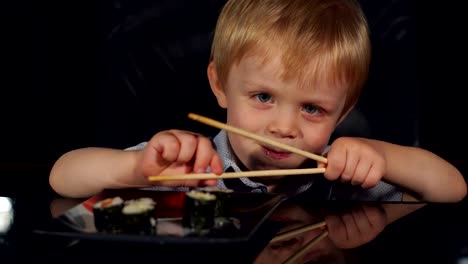 Niedlicher-kleine-Junge-Sushi-Essen-mit-hölzernen-Stäbchen.