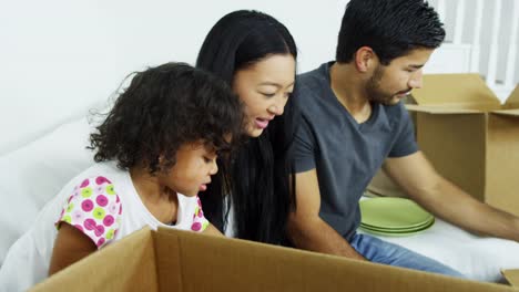 Ethnic-parents-playing-baby-daughter-in-new-home