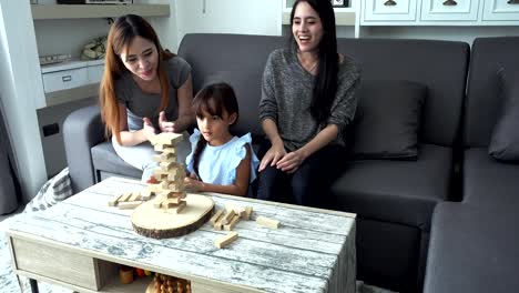 Young-girl-playing-game-with-mother-and-asian-nanny-in-living-room.