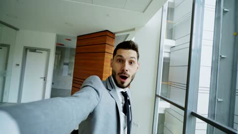 POV-jungen-Geschäftsmann-im-Anzug-Selfie-fotografieren-und-amüsieren-Sie-sich-im-modernen-Büro