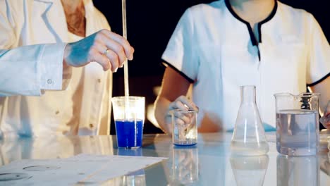 Professional-chemist-in-a-lab-coat-is-experimenting-by-mixing-liquid-chemicals-in-flasks.