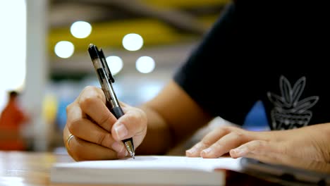 Close-up-shot-hands-of-woman-writing-on-paper-notebook-select-focus-shallow-depth-of-field