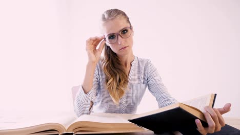 a-girl-sitting-at-a-table-in-the-Office-reads-a-lot-of-books