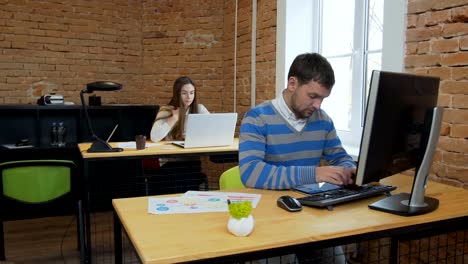 Closeup.-Porträt-einer-schönen-jungen-Frau-und-Mann,-die-auf-dem-Computer-im-Büro-arbeiten.