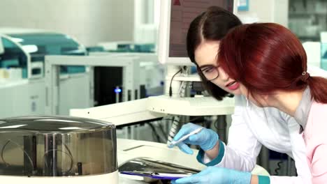 Close-up-of-two-female-biologists-making-notes-while-conducting-experiments