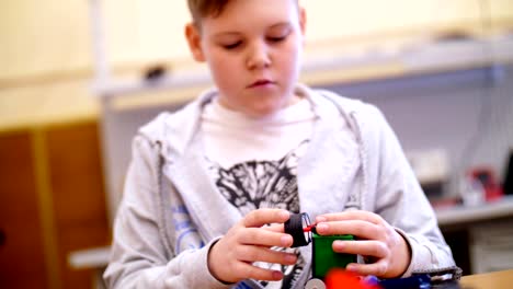 el-niño-de-11-años,-juega-en-el-diseñador-de-cubos,-placas,-circuitos,-cables.-un-pequeño-inventor-crea-robots,-máquinas-de-diferentes-partes-del-diseñador