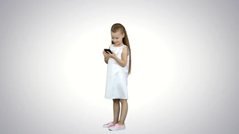 Cute-little-girl-smiling-and-uses-a-mobile-phone-on-white-background