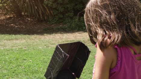 Young-little-girl-flying-a-drone-playing-outdoor-on-summer-in-green-grass-field-remote-pilot-slow-motion