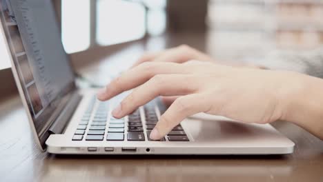 Young-business-man-using-laptop-computer-and-smartphone-on-wooden-desk-in-working-space.-Male-hand-typing-on-laptop-keyboard.-Freelance-lifestyle-in-digital-age-concept.