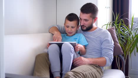 Entspannte-Vater-mit-seinem-Sohn-etwas-auf-dem-tablet