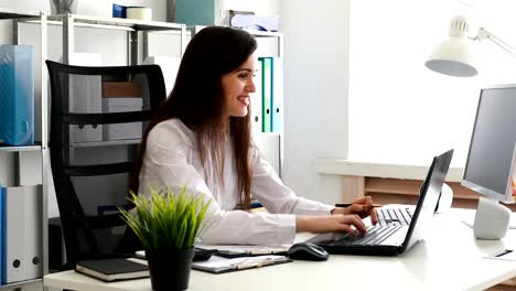 businesswoman-looking-in-documents-and-working-on-laptop-in-modern-office