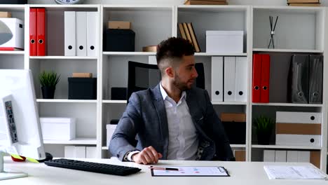 Geschäftsmann-in-graue-Jacke-sitzt-am-Tisch-in-weiß-Büro,-Drucken-auf-der-Tastatur-und-Papiere-zu-werfen