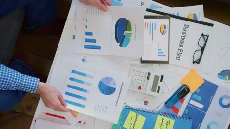 Overhead-Of-Businessman-Reviewing-Various-Financial-Graphs-At-Desk-4K