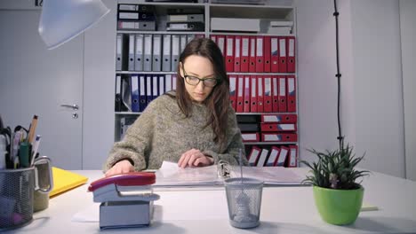 Mujer-leyendo-a-través-de-archivos-en-la-carpeta-de-anillo