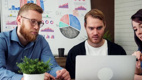 Group-of-young-business-people-working-and-communicating-at-the-office-desk-looking-at-the-laptop-computer