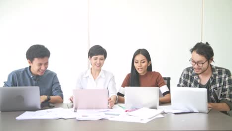 Business-Meeting.-Starten-Sie-klein-Business-Meeting-im-Zimmer.-Asiatische-Mannschaft-mit-Mann-und-Frau-ihre-Arbeit-beenden-und-feiern,-hinsetzen,-face-Kamera.-Neues-Business-Modell-starten-Sie-Konzepte.