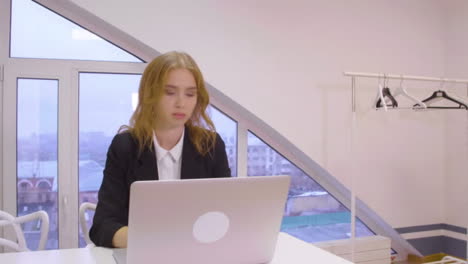 Focused-business-woman-making-financial-report-on-laptop-computer-in-office