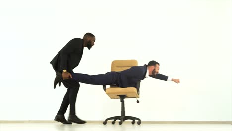 The-two-happy-businessmen-playing-with-an-office-chair.-slow-motion