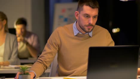 trabajadores-de-oficina-con-el-portátil-trabajando-por-la-noche