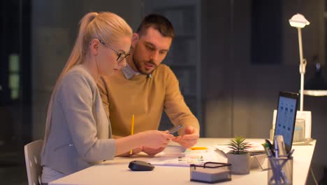 equipo-de-negocios-con-ordenador-portátil-a-trabajar-en-oficina-de-noche