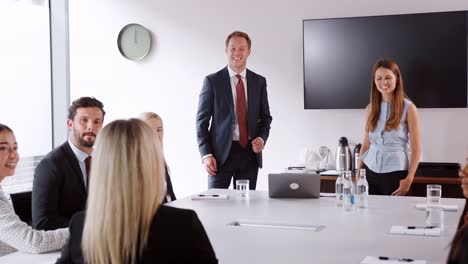 Young-Businessman-And-Businesswoman-Addressing-Group-Meeting-Around-Table-At-Graduate-Recruitment-Assessment-Day