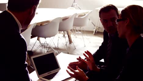 Serious-business-people-working-together-while-looking-laptop